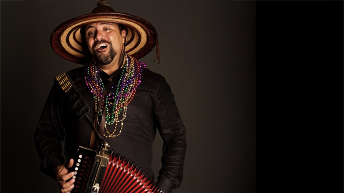 Terrance Simien wearing pointed hat, playing accordion.