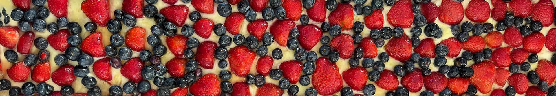 Closeup of blueberries and strawberries thickly strewn over pastry