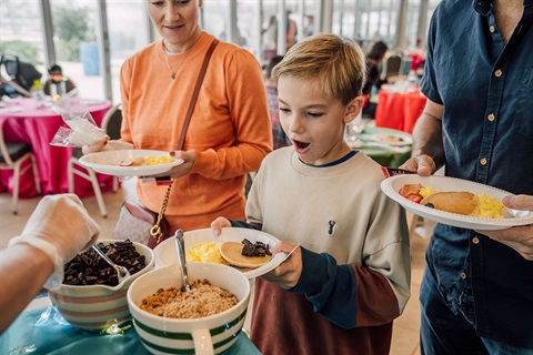 Little boy gapes as a server heaps chocolate chips on his pancakes.