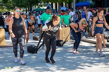 The annual event included a Crossfit challenge. Here two women are pulling weight sleds as a spotter walks along side.
