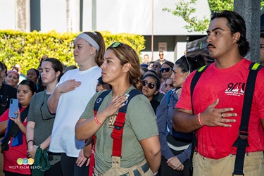 Three participants stand with hands over their hearts paying respect during the singing of the National Anthem.