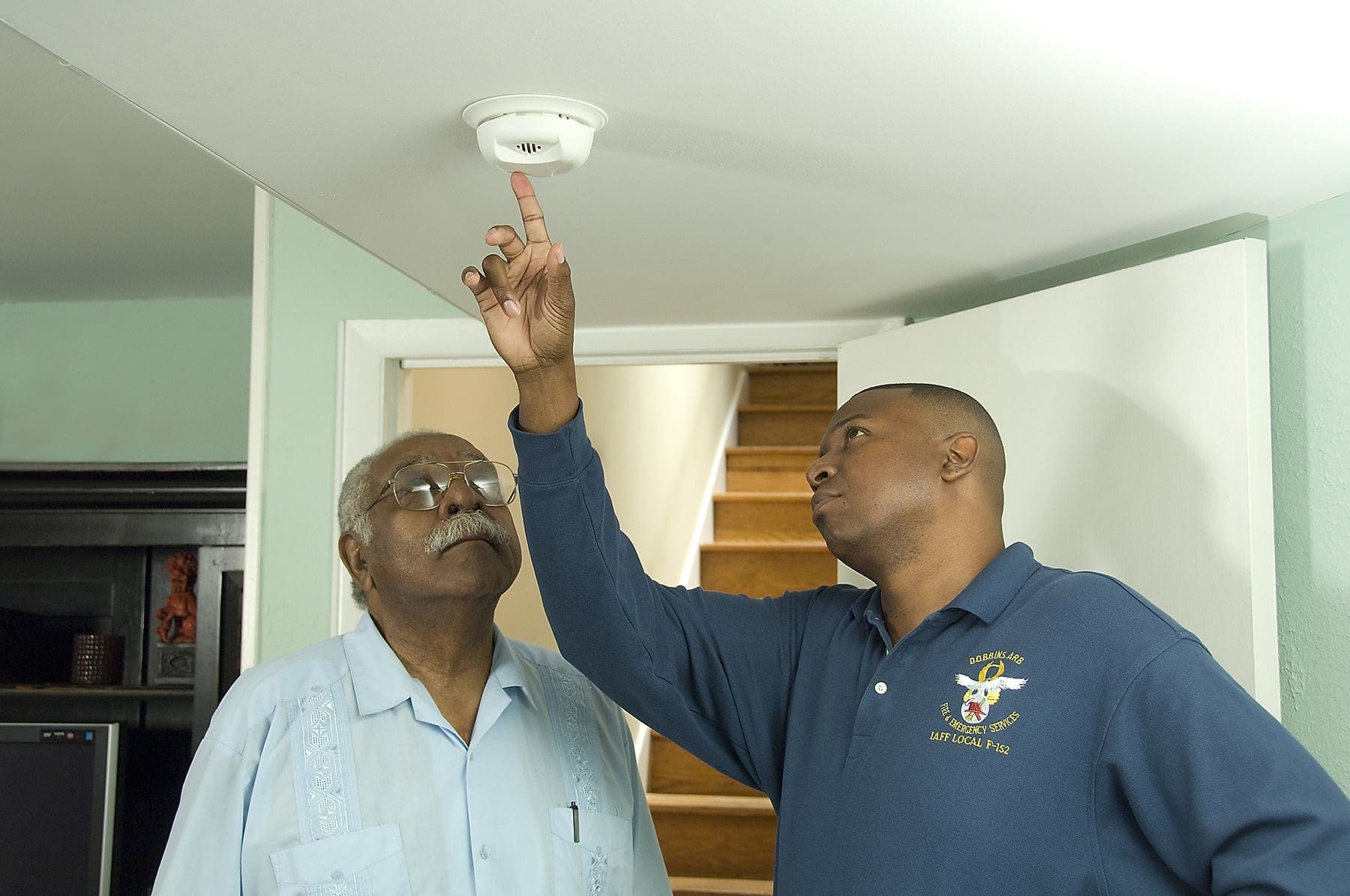 Two men testing a smoke alarm