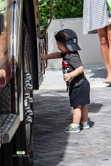 Curious about a fire truck, a little boy touches the unit