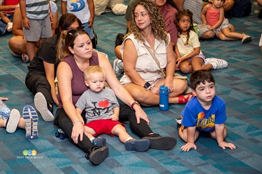 Two moms with their children listen as firefighters talk.