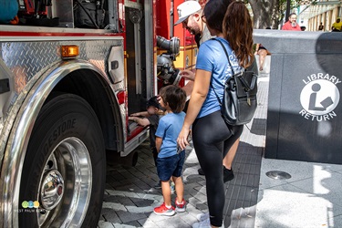 A young man and his mom look at all the gear stored inside the fire truck.