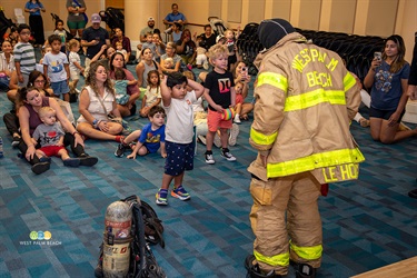 Youngsters stand in awe as a fireman puts on his bunker gear.