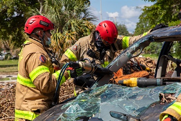 Firefighters cut the roof supports of a car to look for survivors