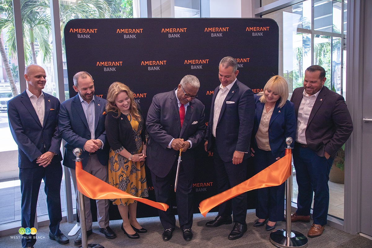 Cutting the ribbon at Amerant Bank, 7 people, Major Keith A. James in the middle with the scissors cutting the ribbon.