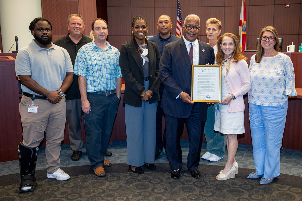 Leah Rockwell accepts the proclamation from Mayor Keith A. James as staff members gather around