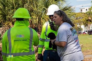 Upset woman actor talks with crew members holding a stuffed dog after the dog was rescued from the debris pile